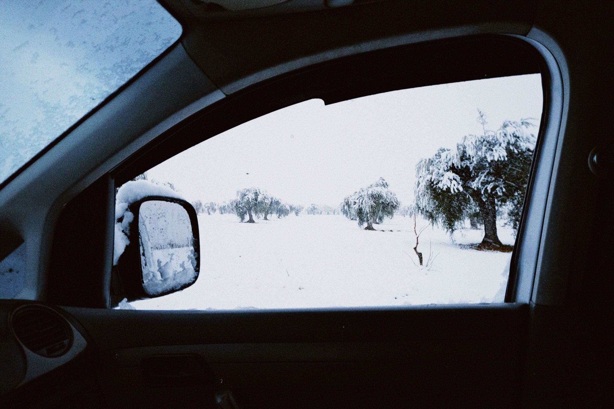 Car window replacement in Billings: snowy field seen through a car side window and mirror