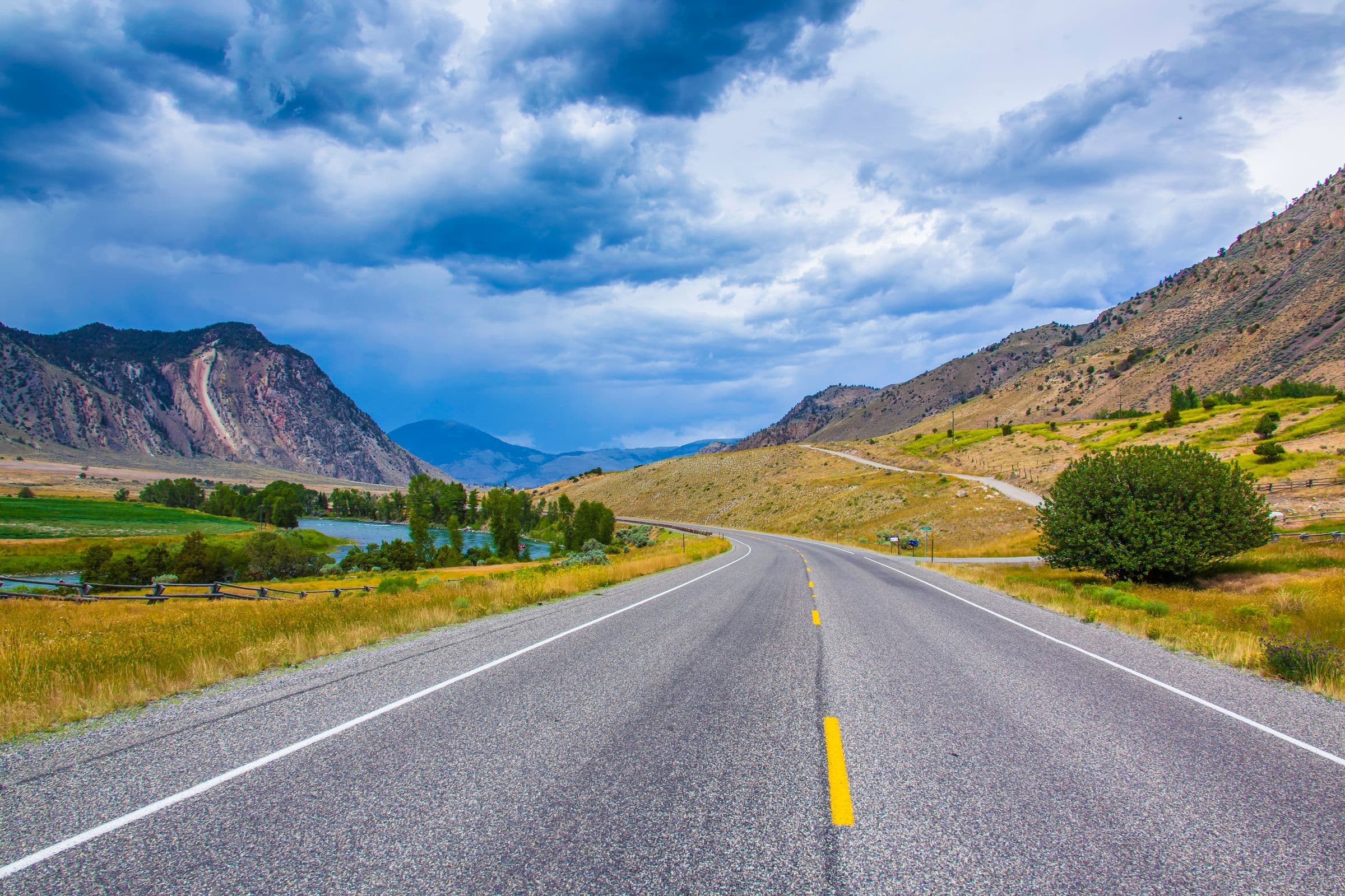 Windshield replacement for Columbus, MT drivers: highway curving along a river valley below rocky hills