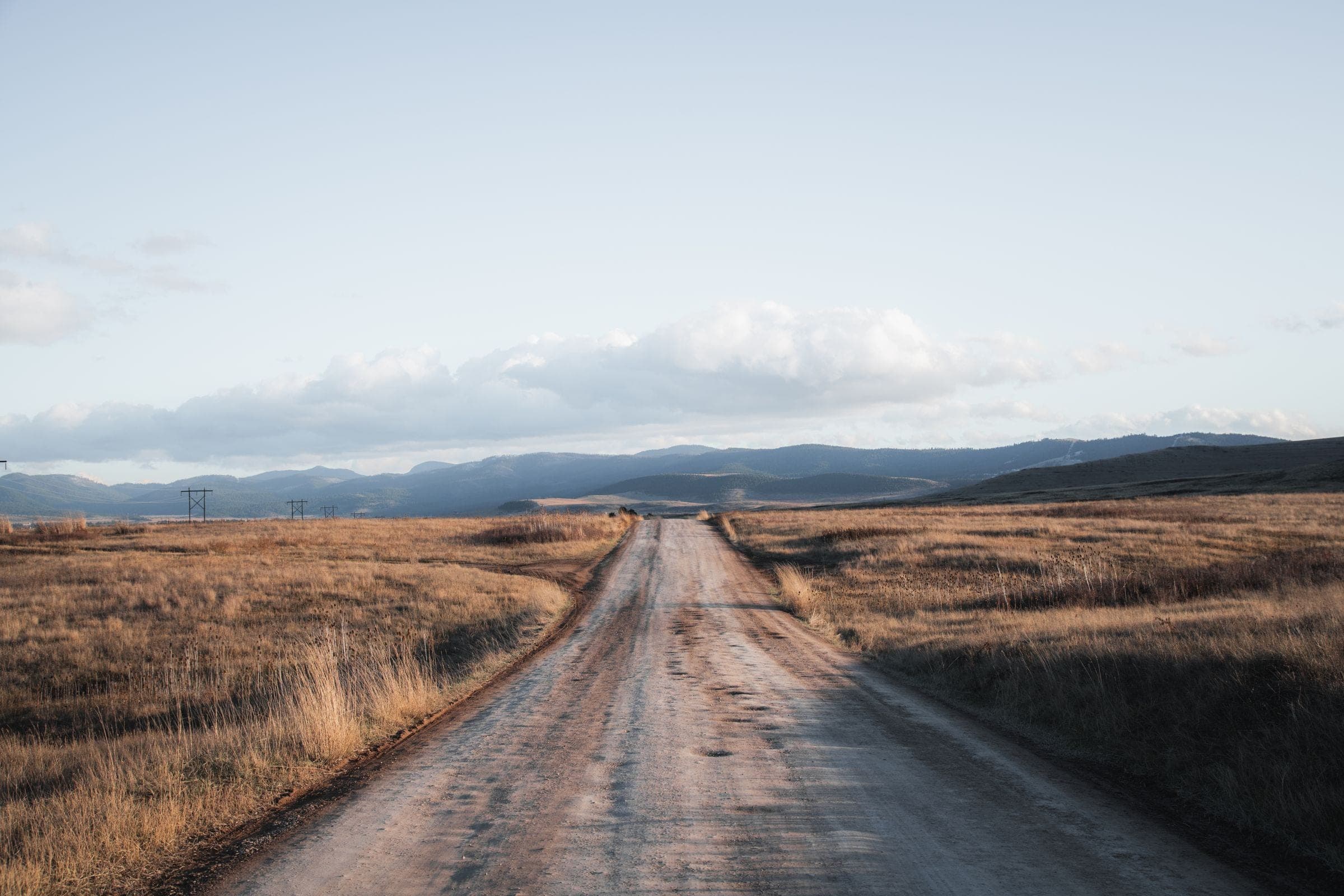 Windshield replacement for Shepherd, MT drivers: gravel county road through golden Montana grassland