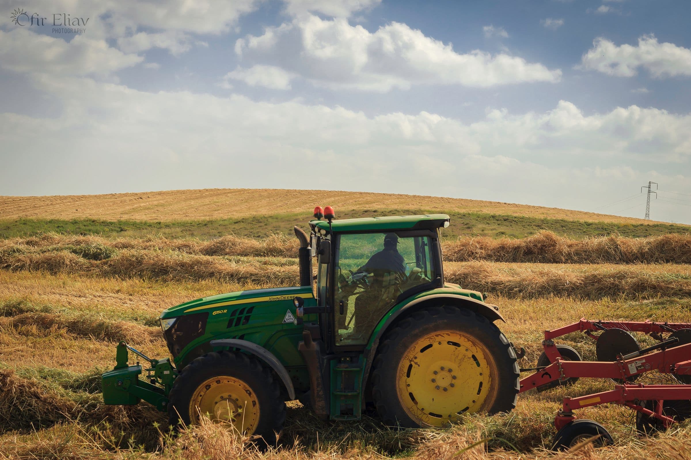 Windshield replacement for Worden, MT drivers: green tractor pulling an implement through a hay field