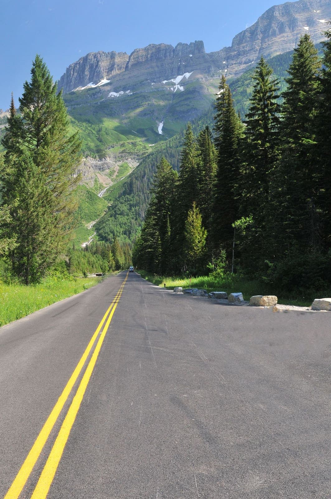Two-lane road through aspens toward mountains