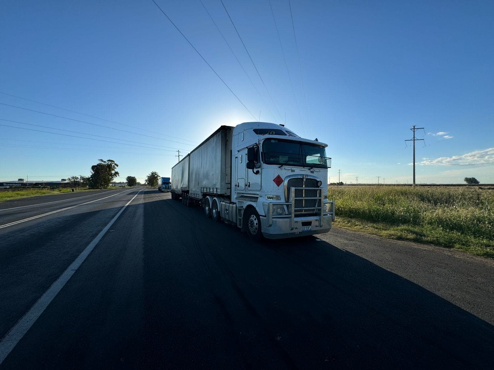Semi truck driving an open highway at sunrise