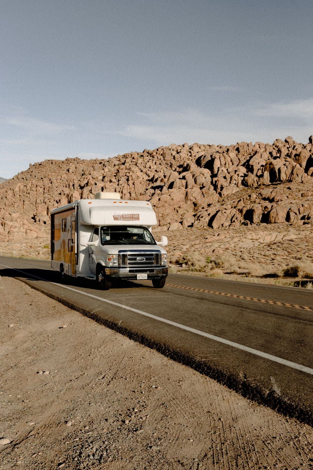 Class C motorhome on a highway past rock formations