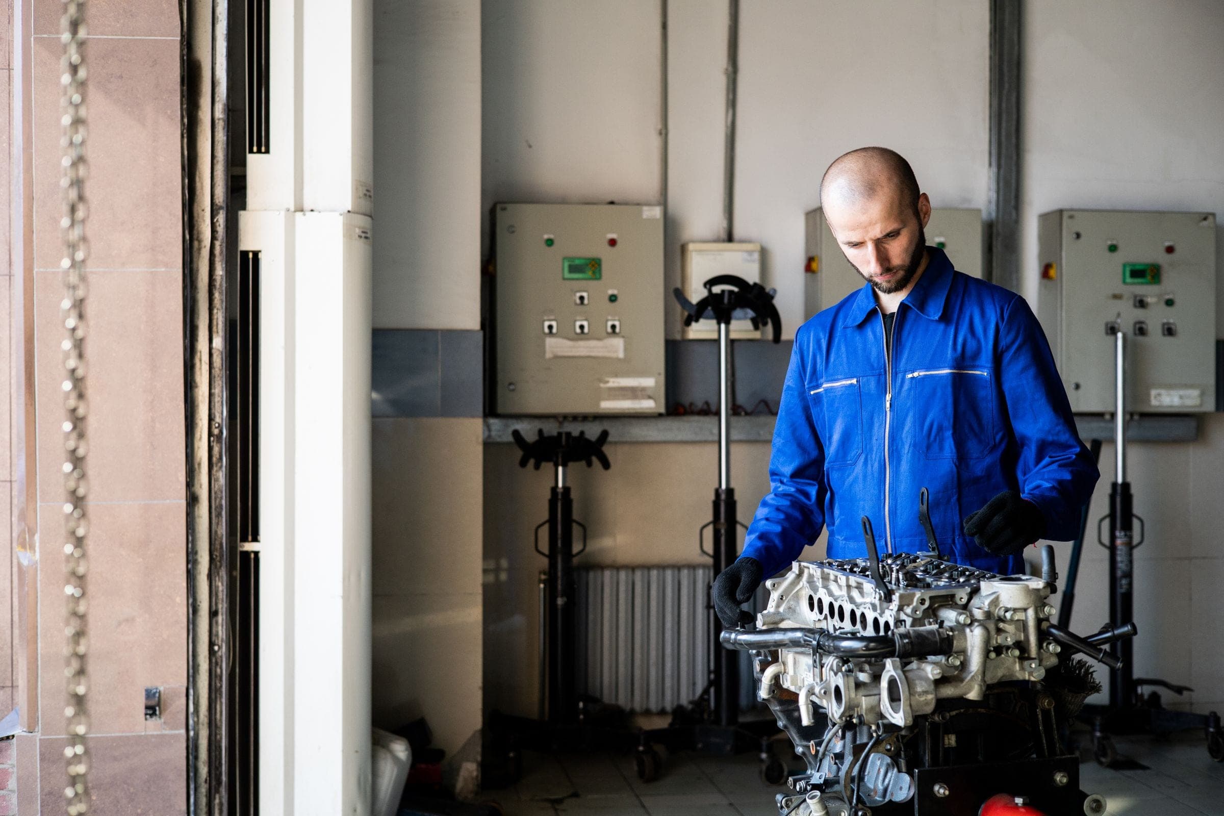 Technician in blue coveralls at a workbench inside the shop