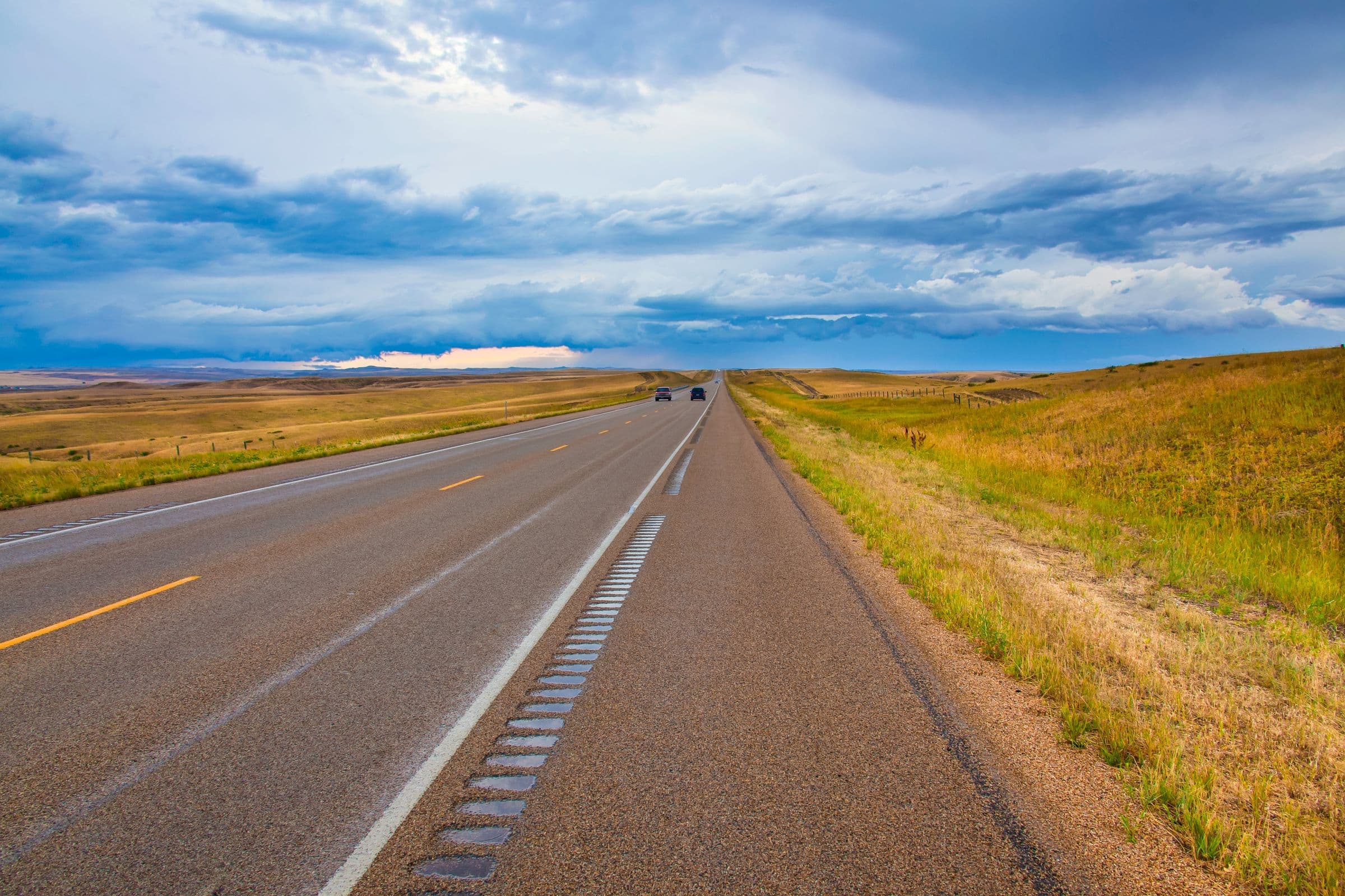 Straight Montana highway running through prairie under a wide sky